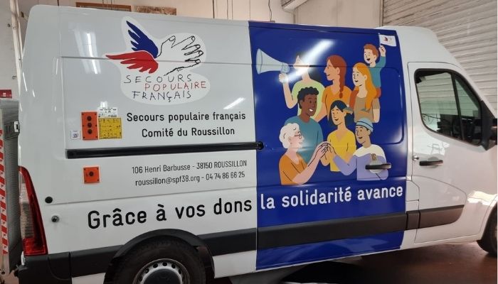 Vue porte latérale du camion floqué du Secours Populaire avec un visuel vectoriel, message d’appel aux dons et coordonnées de contact.